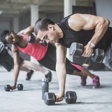 athletes doing pushups with dumbbells on floor