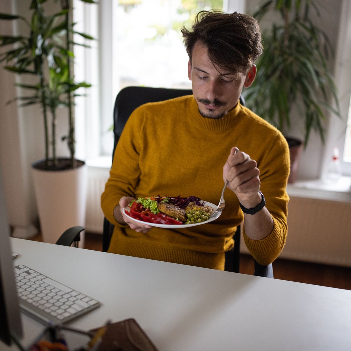 caucasian man working at the office while eating healthy meal