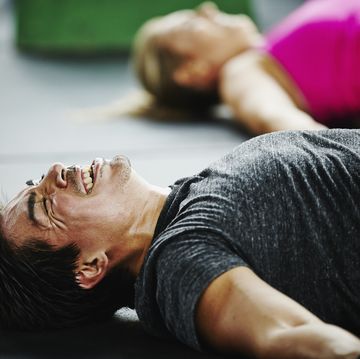 man laughing and grimacing lying on floor of gym gym