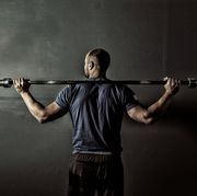 man in gym gym with weight bar on shoulders