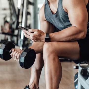 muscular young man training at gym with smart phone