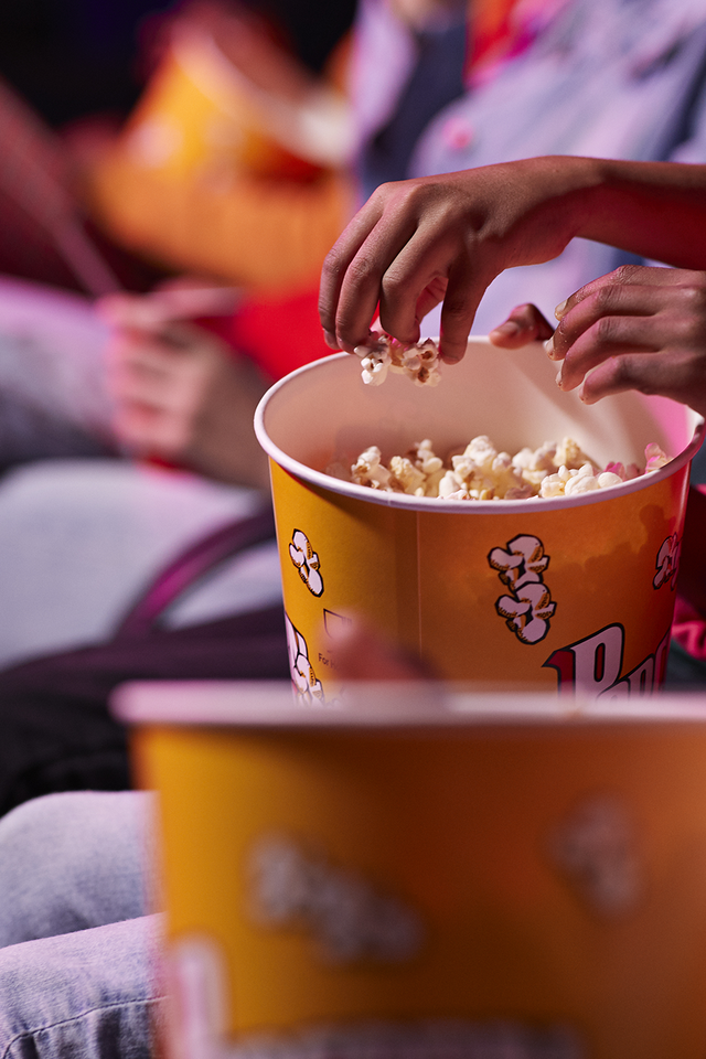 hands sharing popcorn in movie theater